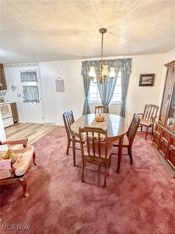 dining space with a notable chandelier, a textured ceiling, and carpet