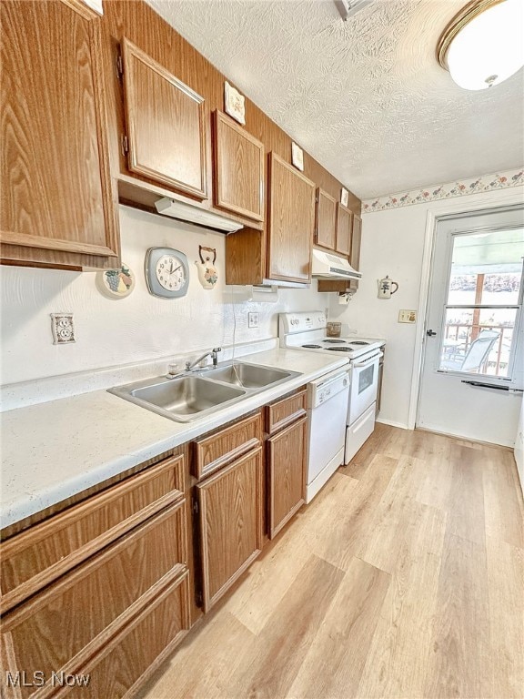 kitchen featuring sink, a textured ceiling, light wood-type flooring, and white appliances