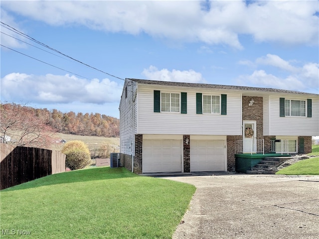 bi-level home featuring central air condition unit, a front lawn, and a garage