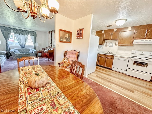 dining space with sink, a textured ceiling, light hardwood / wood-style flooring, and an inviting chandelier