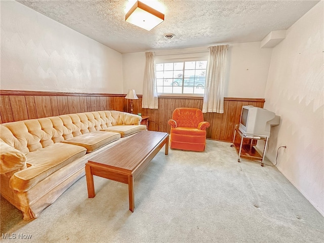 carpeted living room featuring a textured ceiling and wood walls