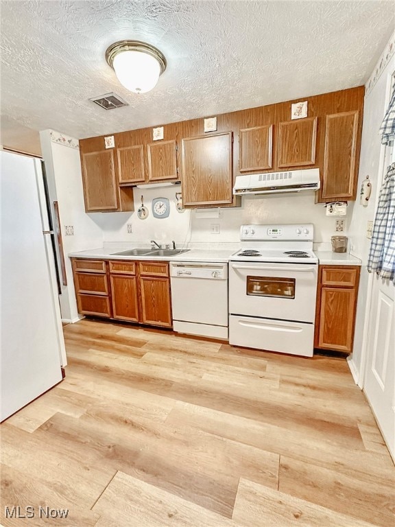 kitchen with white appliances, a textured ceiling, light hardwood / wood-style flooring, and sink