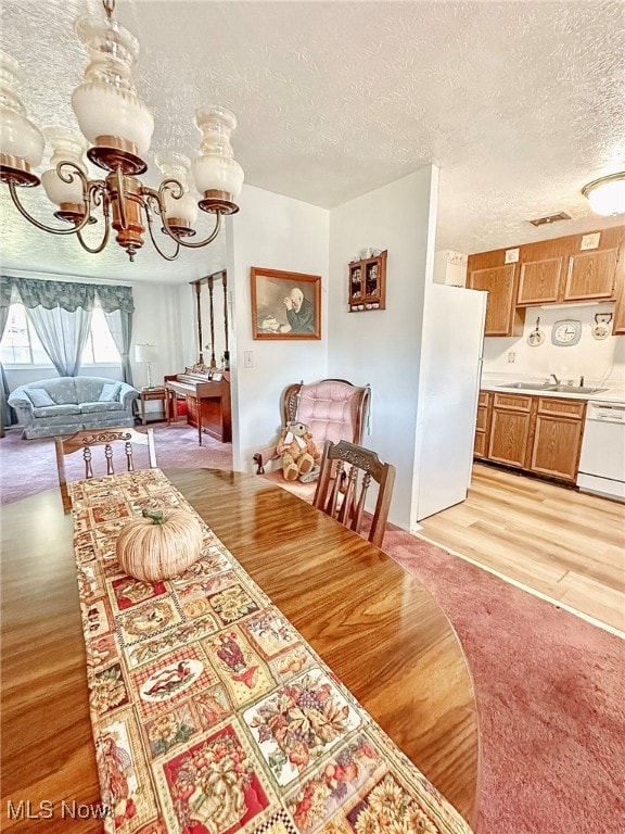 dining space with sink, a textured ceiling, and light hardwood / wood-style floors