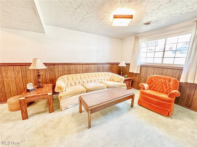 living area featuring carpet flooring, a textured ceiling, and wooden walls