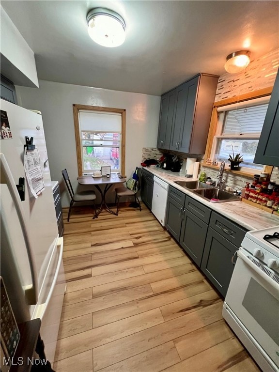 kitchen with light hardwood / wood-style floors, sink, backsplash, and white appliances