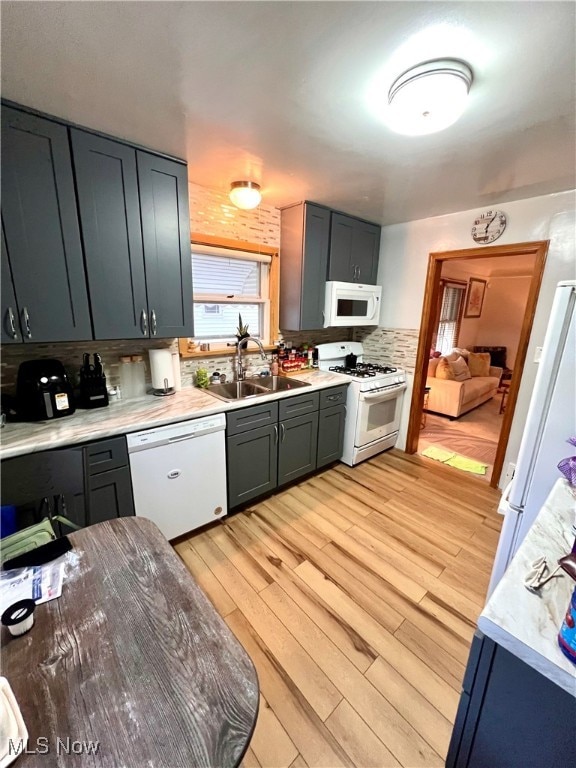 kitchen featuring decorative backsplash, sink, light wood-type flooring, and white appliances