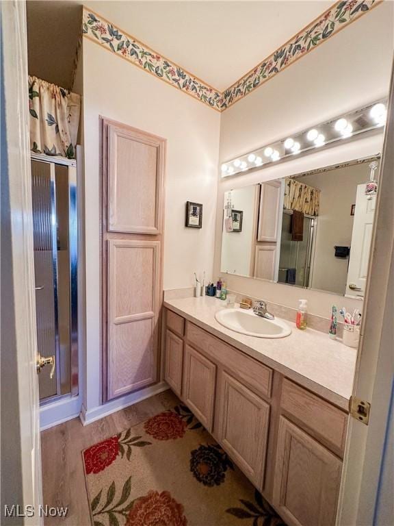 bathroom featuring a stall shower, vanity, and wood finished floors