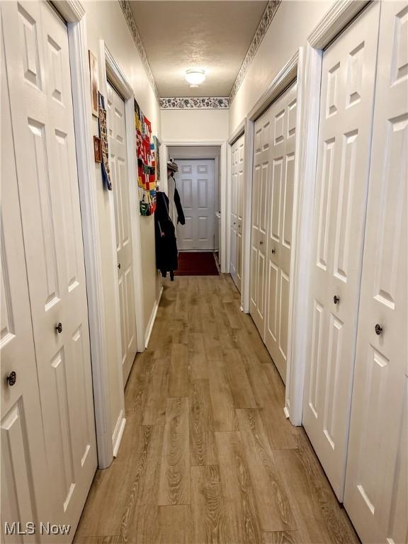 hallway featuring light wood-style flooring and baseboards