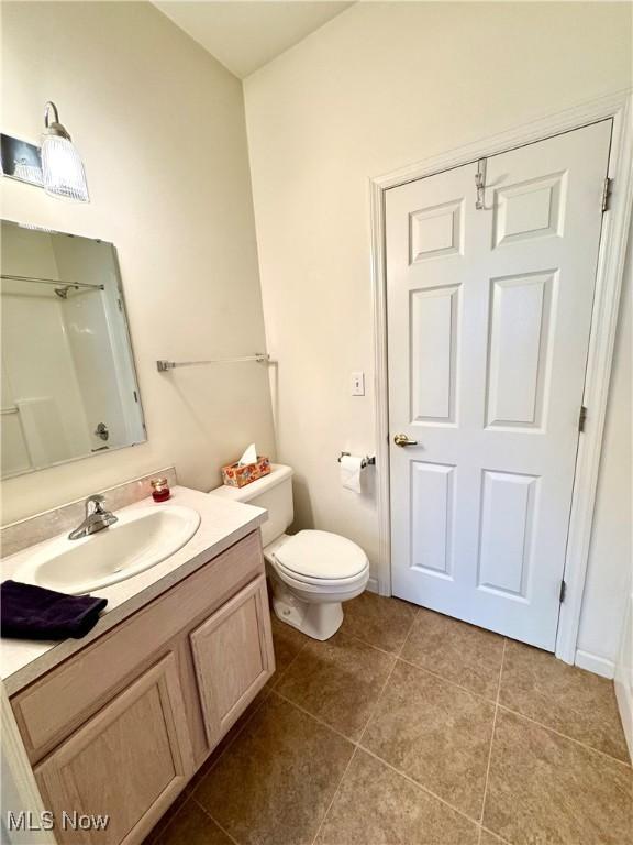 bathroom with toilet, vanity, and tile patterned floors