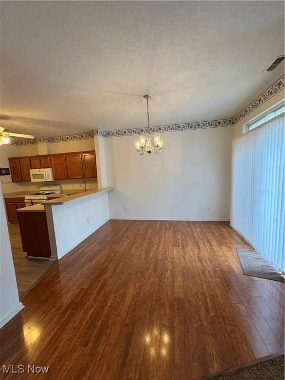 unfurnished living room with baseboards, visible vents, dark wood-style flooring, a textured ceiling, and ceiling fan with notable chandelier