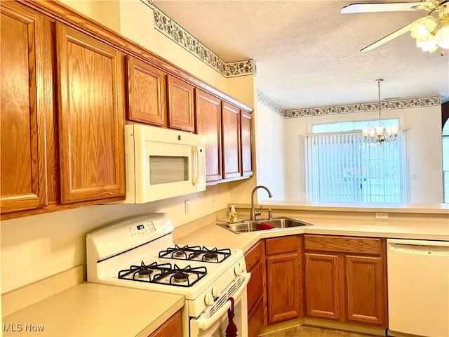 kitchen with white appliances, light countertops, a sink, and a textured ceiling