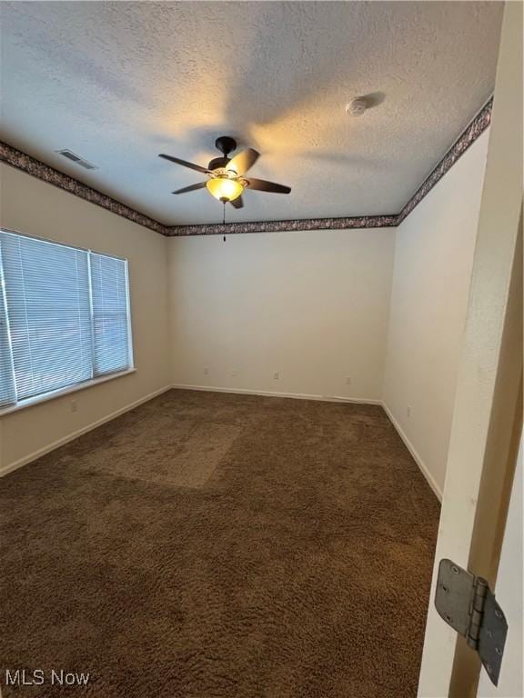 unfurnished room with baseboards, visible vents, a ceiling fan, a textured ceiling, and dark carpet