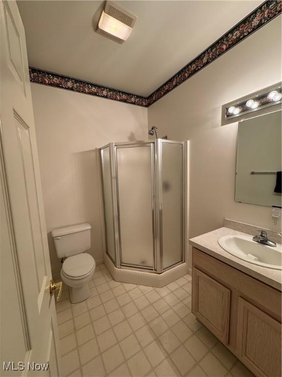 full bathroom with toilet, a stall shower, visible vents, and vanity