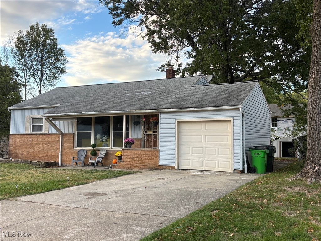 ranch-style home with a garage, a front yard, and covered porch