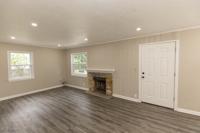 unfurnished living room featuring a stone fireplace, dark wood-type flooring, and ornamental molding