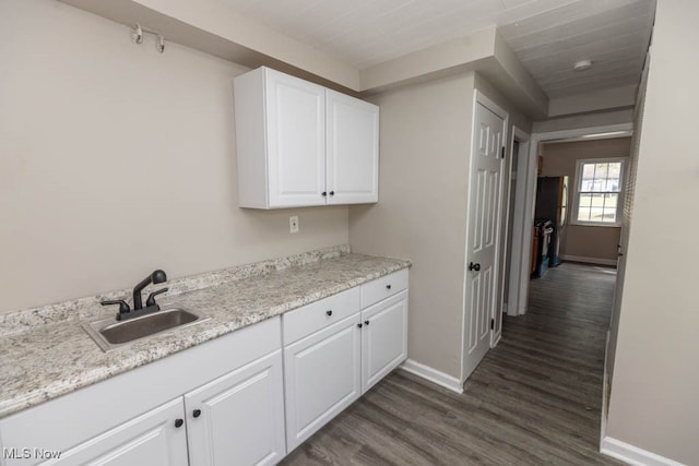 kitchen featuring white cabinets, sink, dark wood-type flooring, and light stone counters