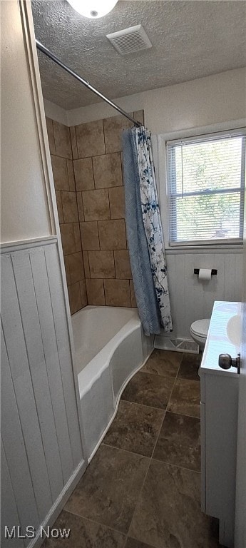 full bathroom with toilet, wood walls, a textured ceiling, vanity, and shower / tub combo with curtain