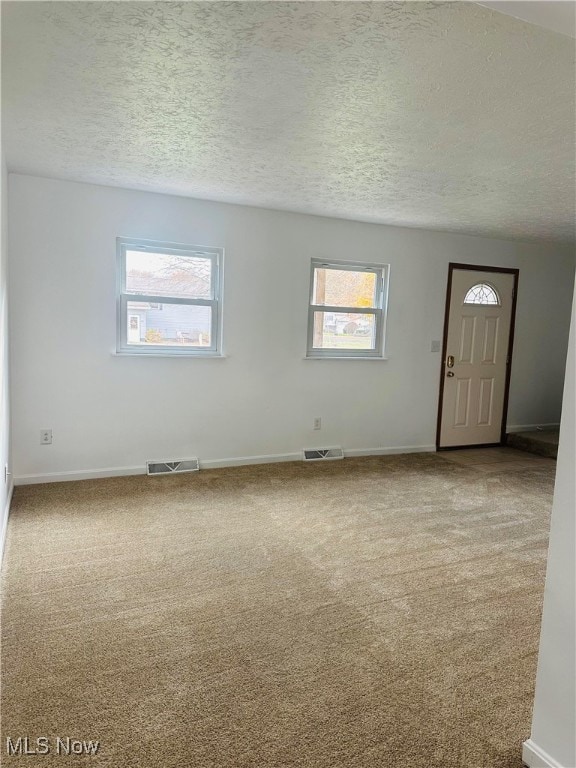 spare room featuring carpet flooring and a textured ceiling