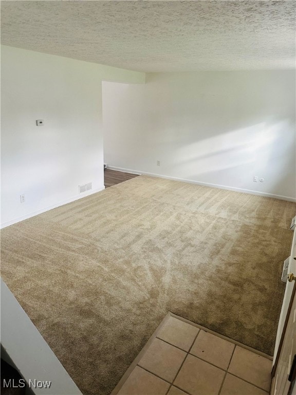 empty room with carpet floors and a textured ceiling