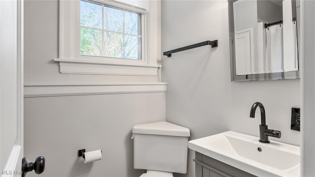 bathroom featuring toilet, vanity, and curtained shower