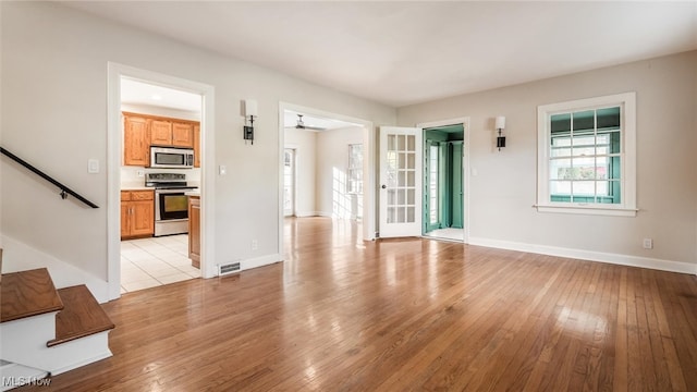 unfurnished living room with light wood-type flooring and ceiling fan