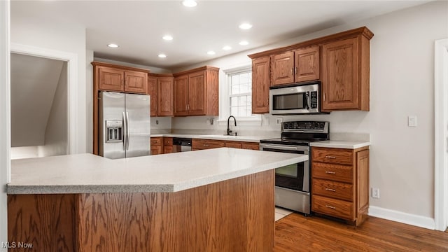 kitchen featuring stainless steel appliances, hardwood / wood-style flooring, sink, and kitchen peninsula