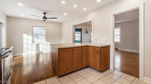 kitchen featuring ceiling fan, kitchen peninsula, stainless steel range oven, and light hardwood / wood-style floors