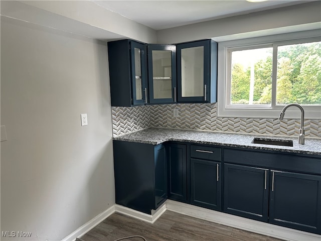 kitchen featuring dark hardwood / wood-style flooring, light stone counters, sink, and tasteful backsplash