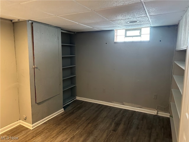 basement with dark hardwood / wood-style flooring and a drop ceiling