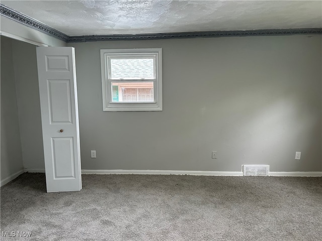 carpeted empty room featuring a textured ceiling