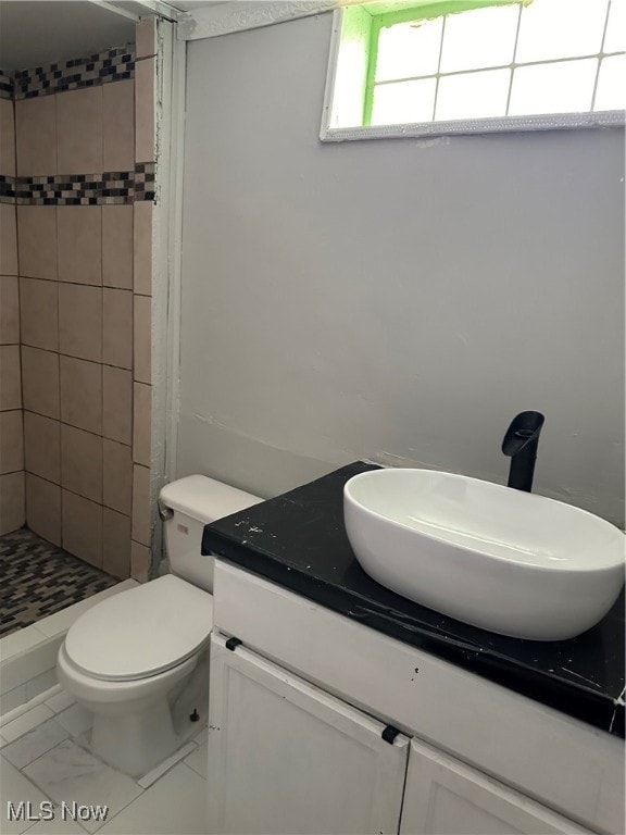 bathroom featuring tiled shower, vanity, and toilet