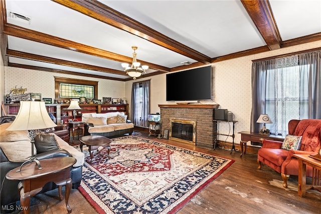 living room with a brick fireplace, dark wood-type flooring, a notable chandelier, ornamental molding, and beam ceiling