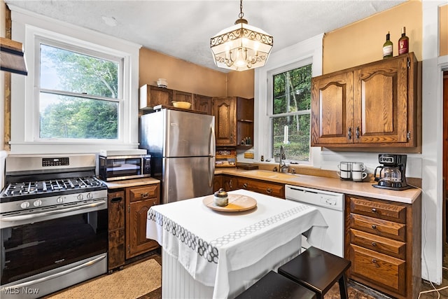 kitchen featuring a healthy amount of sunlight, sink, decorative light fixtures, and appliances with stainless steel finishes