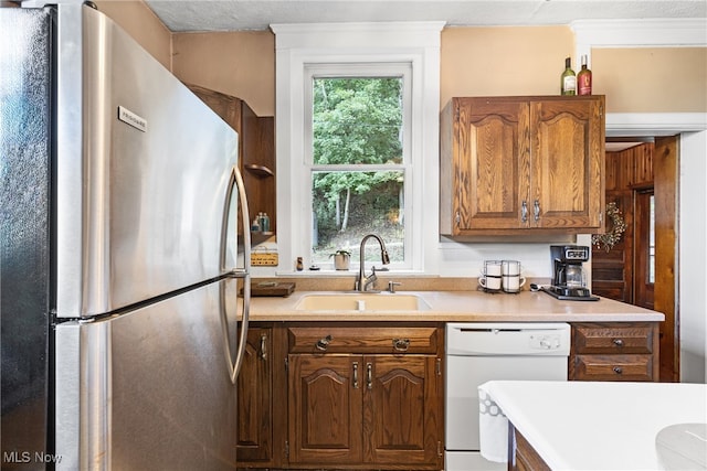 kitchen featuring dishwasher, sink, stainless steel refrigerator, and a textured ceiling