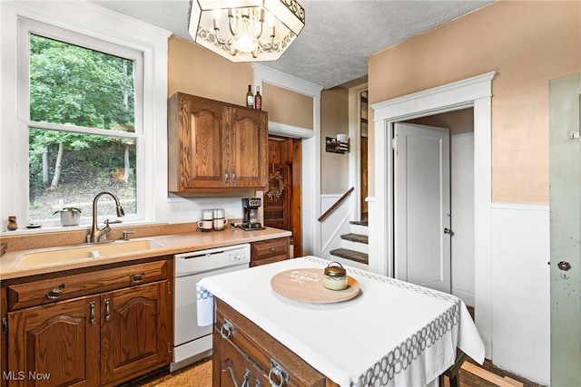 kitchen featuring sink, a healthy amount of sunlight, white dishwasher, and a textured ceiling