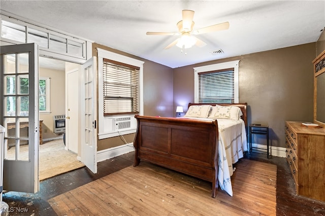 bedroom featuring cooling unit, wood-type flooring, ceiling fan, and heating unit