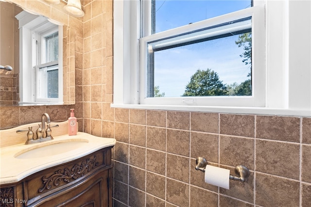 bathroom with tile walls, vanity, and a healthy amount of sunlight