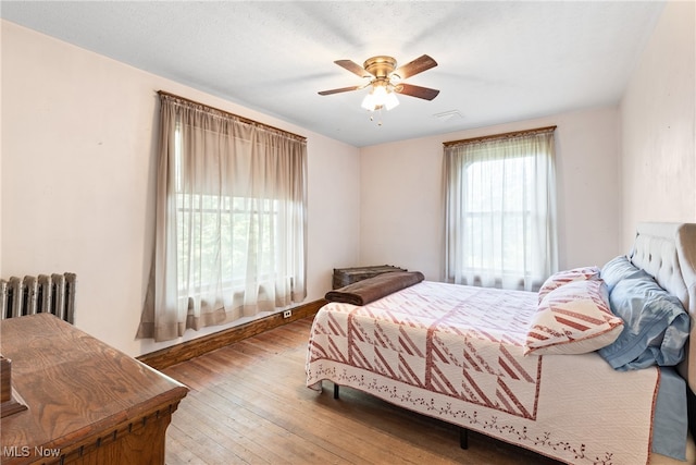 bedroom featuring radiator, ceiling fan, and hardwood / wood-style flooring