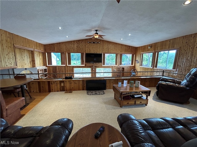 carpeted living room with wood walls, a wealth of natural light, a textured ceiling, and ceiling fan