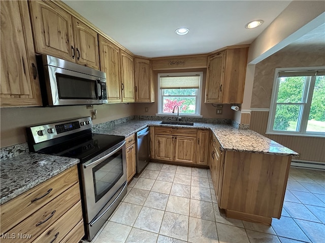 kitchen featuring dark stone counters, appliances with stainless steel finishes, sink, a baseboard radiator, and kitchen peninsula