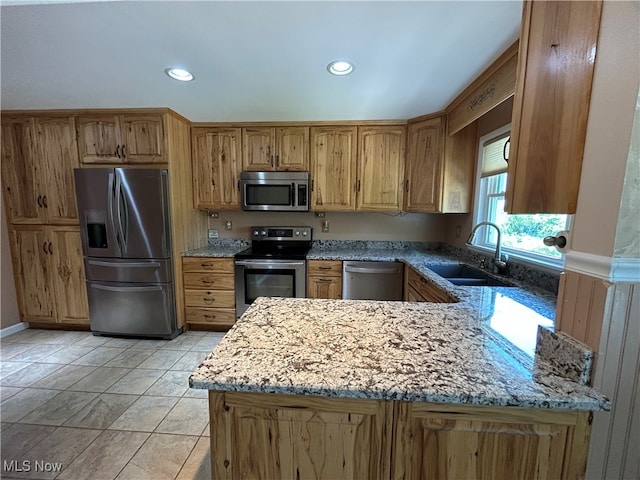 kitchen with light stone countertops, kitchen peninsula, sink, and stainless steel appliances