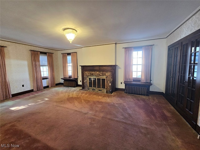 unfurnished living room featuring radiator, french doors, crown molding, and carpet floors