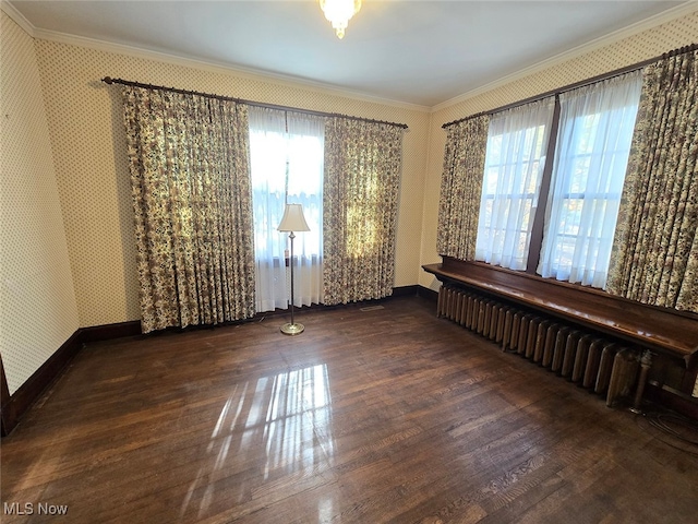 unfurnished room featuring dark wood-type flooring, radiator, a wealth of natural light, and ornamental molding