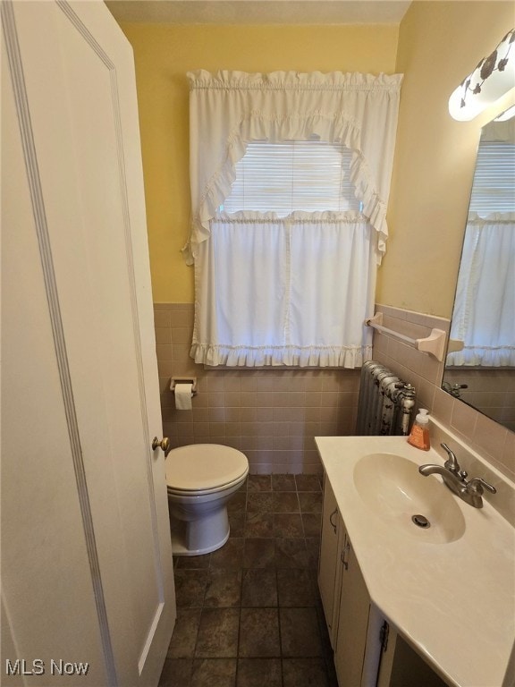 bathroom with toilet, radiator, tile walls, tile patterned flooring, and vanity