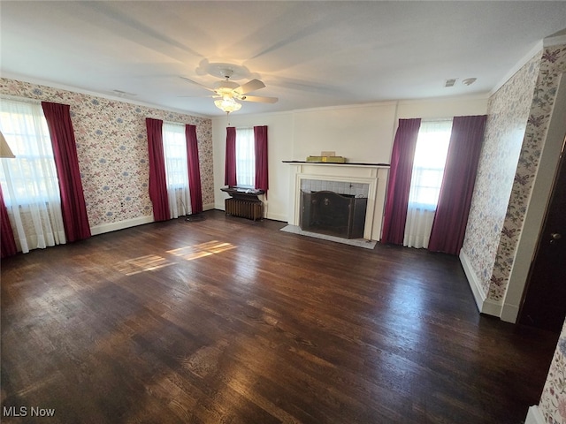 unfurnished living room featuring radiator, ceiling fan, dark hardwood / wood-style floors, and a fireplace