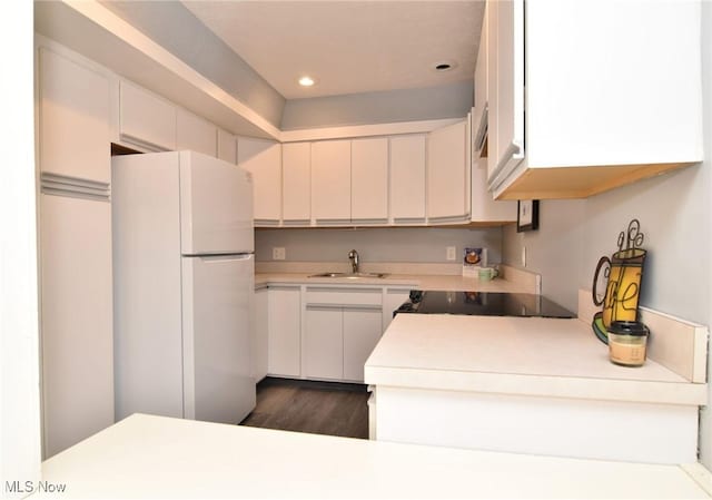 kitchen with white cabinets, white refrigerator, black stove, sink, and dark hardwood / wood-style floors