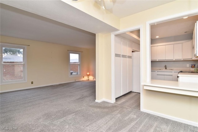 interior space featuring light carpet, plenty of natural light, and sink