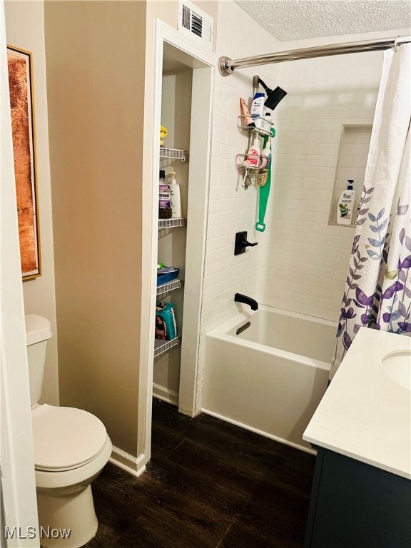 full bathroom featuring hardwood / wood-style floors, shower / bath combination with curtain, a textured ceiling, toilet, and vanity