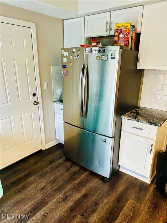 kitchen with decorative backsplash, stainless steel fridge, dark hardwood / wood-style flooring, dark stone countertops, and white cabinets