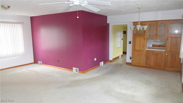 interior space with light carpet, ceiling fan with notable chandelier, and a textured ceiling